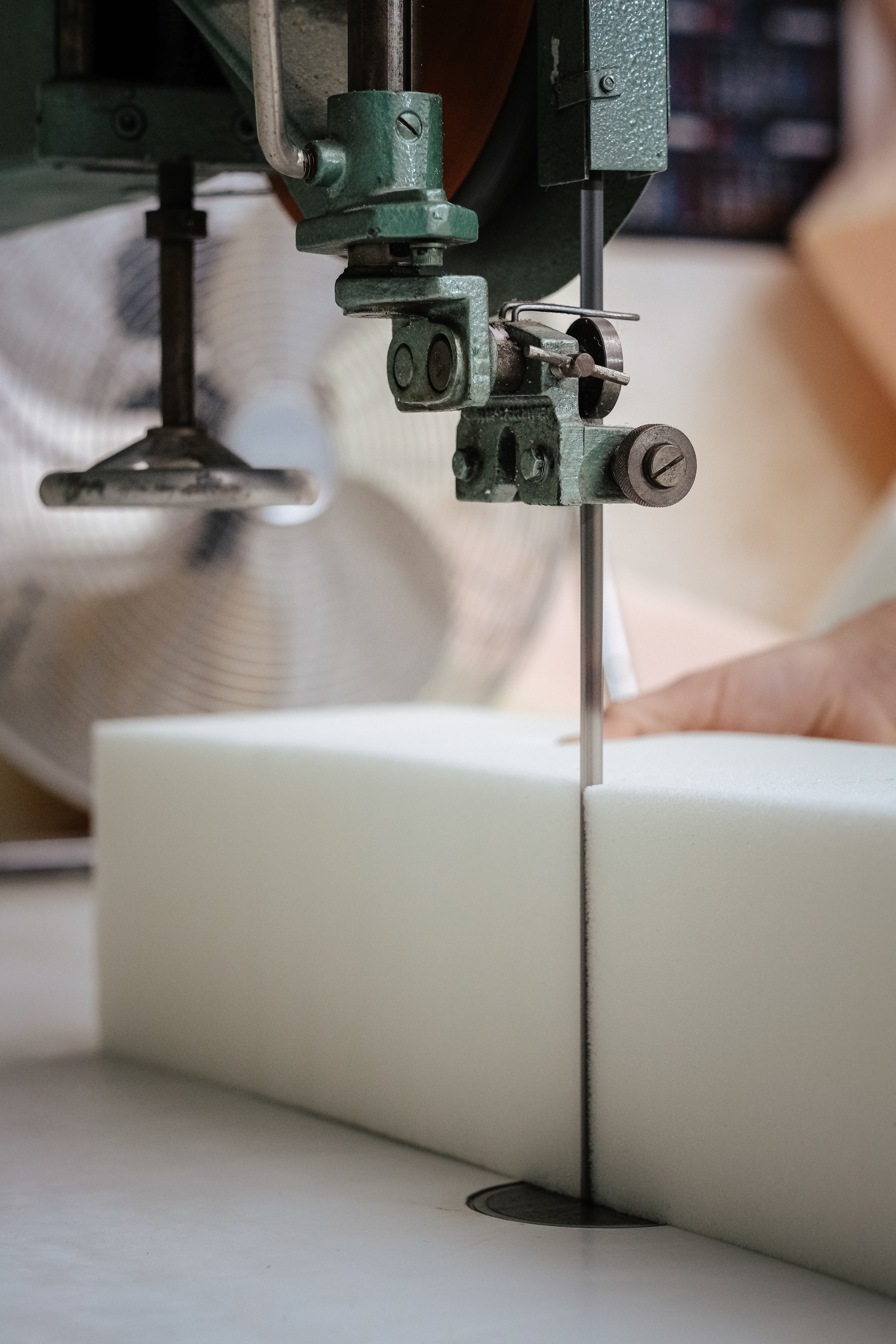 Vertical shot of a foam cutter machine, cutting through an upholstery foam